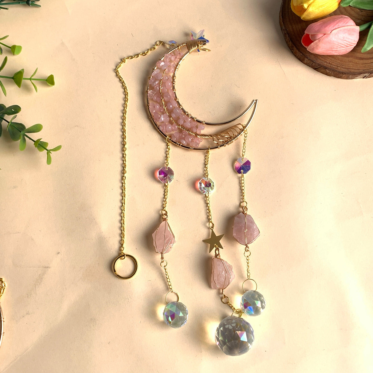 Handgefertigter Mond-Sonnenfänger mit Rosenquarz-Chips, goldfarbenem Rahmen und vier Strängen, bestückt mit rohen Rosenquarz-Anhängern und facettierten Lichtkristallkugeln.