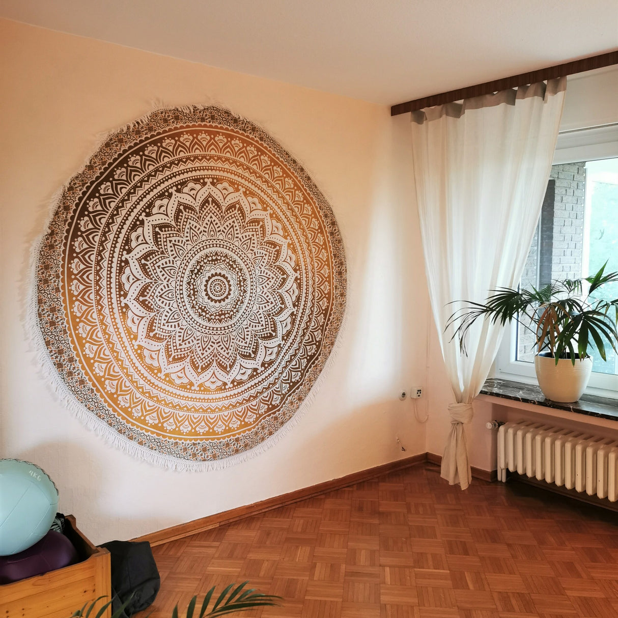 Rundes Strandtuch mit Ombre Mandala in ocker braun an der Wand