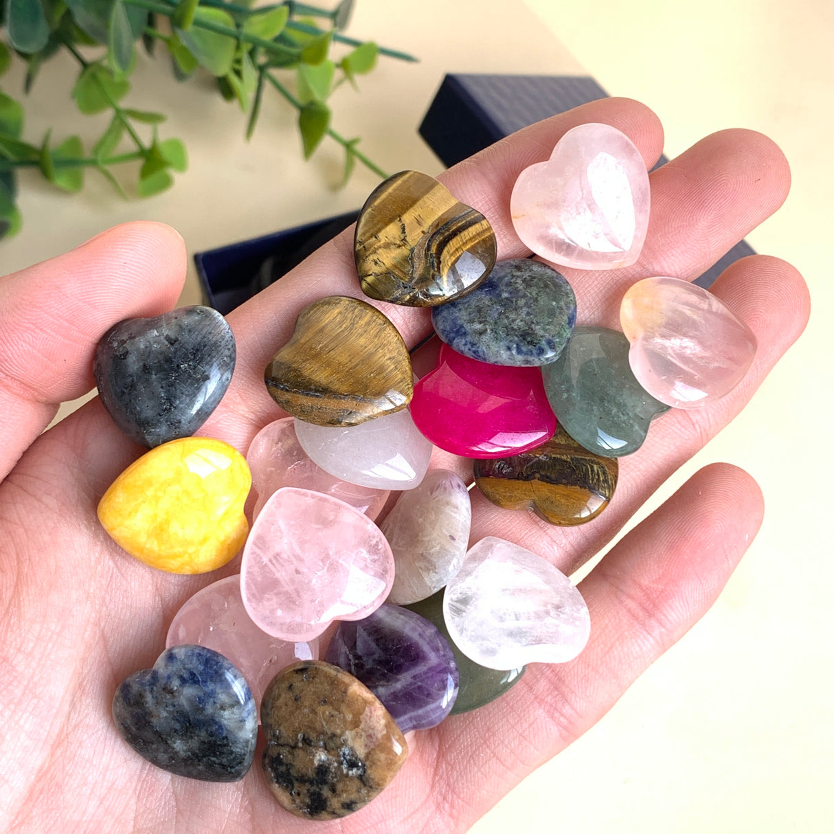 Bunte Edelstein Herzen in der Hand gehalten, polierte Natursteine wie Rosenquarz, Lapislazuli und Tigerauge für Rituale und Meditation