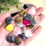 Bunte Edelstein Herzen in der Hand gehalten, polierte Natursteine wie Rosenquarz, Lapislazuli und Tigerauge für Rituale und Meditation