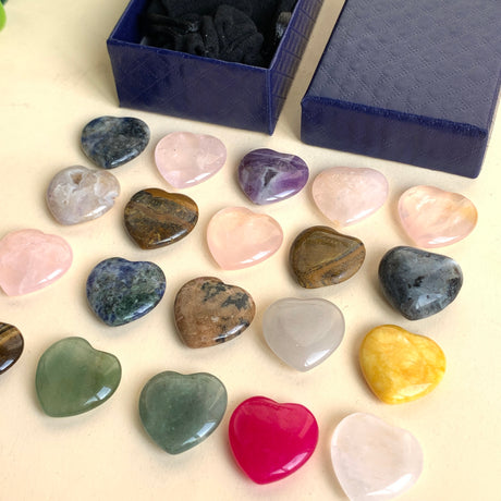 Edelstein Herzen Set mit polierten Herzsteinen aus Rosenquarz, Amethyst, Aventurin und weiteren Natursteinen vor blauer Schmuckbox