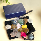 Edelstein Herzen Set im schwarzen Samtbeutel mit bunter Mischung polierter Herzsteine vor dunkelblauer Schmuckbox