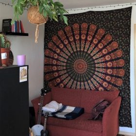 Pfauenfeder Mandala in grün orange als Wandbehang im Wohnzimmer