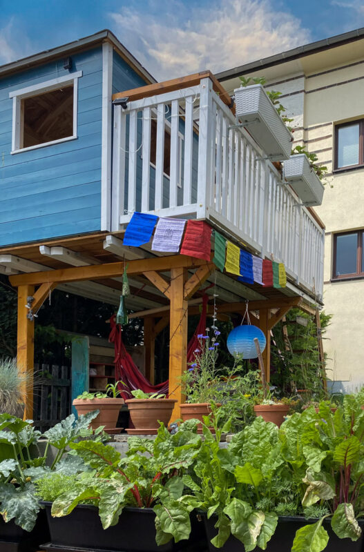 Schönes blaues Holzhaus mit Hängematte, Laterne und bunten Gebetsfahnen